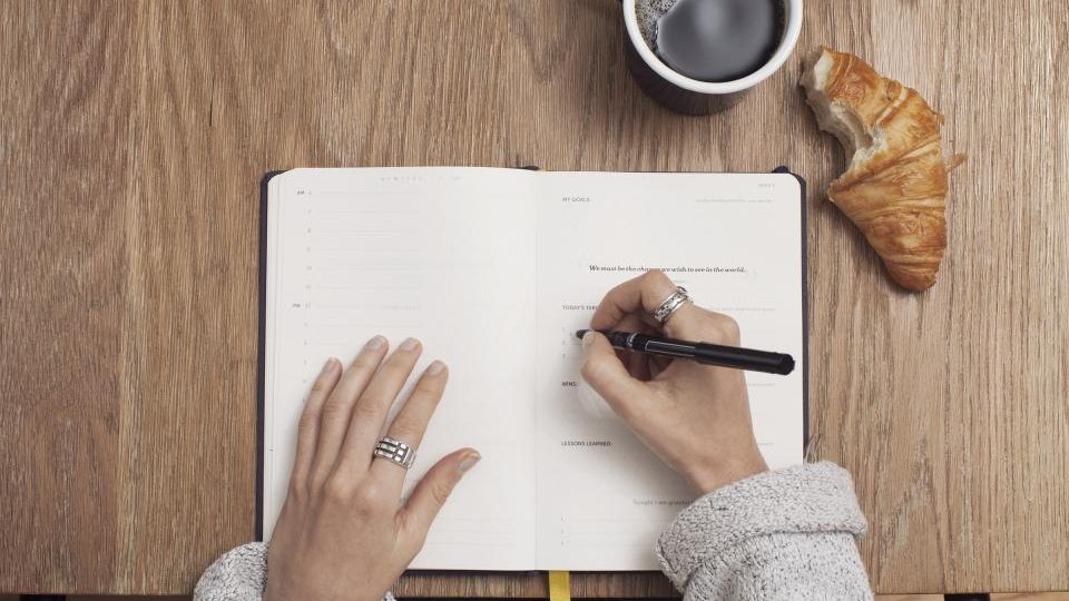Carnet ouvert, café et stylo sur un bureau en bois